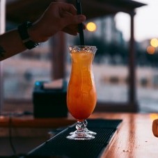 A bartender using a straw and stirring a refreshing cocktail at the Beach Club Restaurant