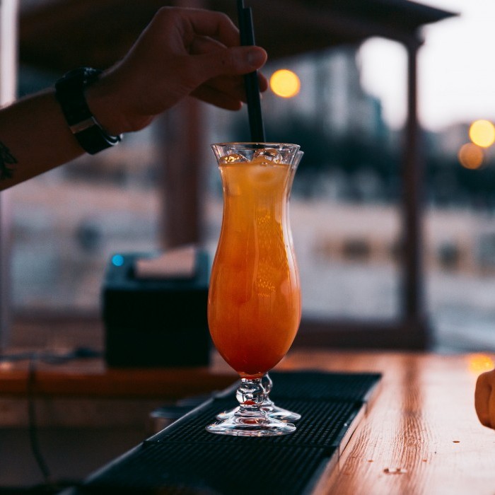 A bartender using a straw and stirring a refreshing cocktail at the Beach Club Restaurant