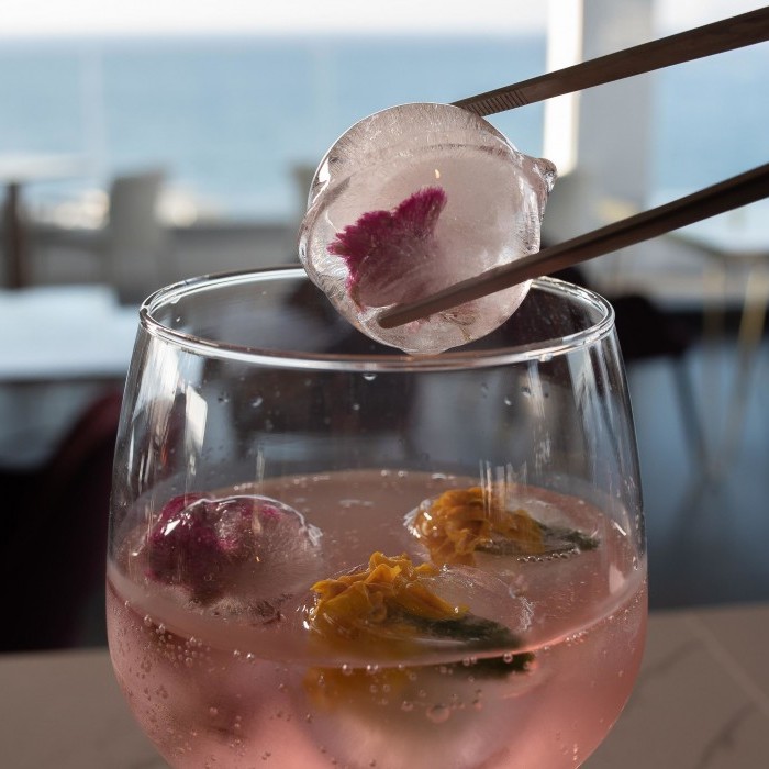 Pomegranate Infused Tanqueray Gin with edible flowers and rose water spray